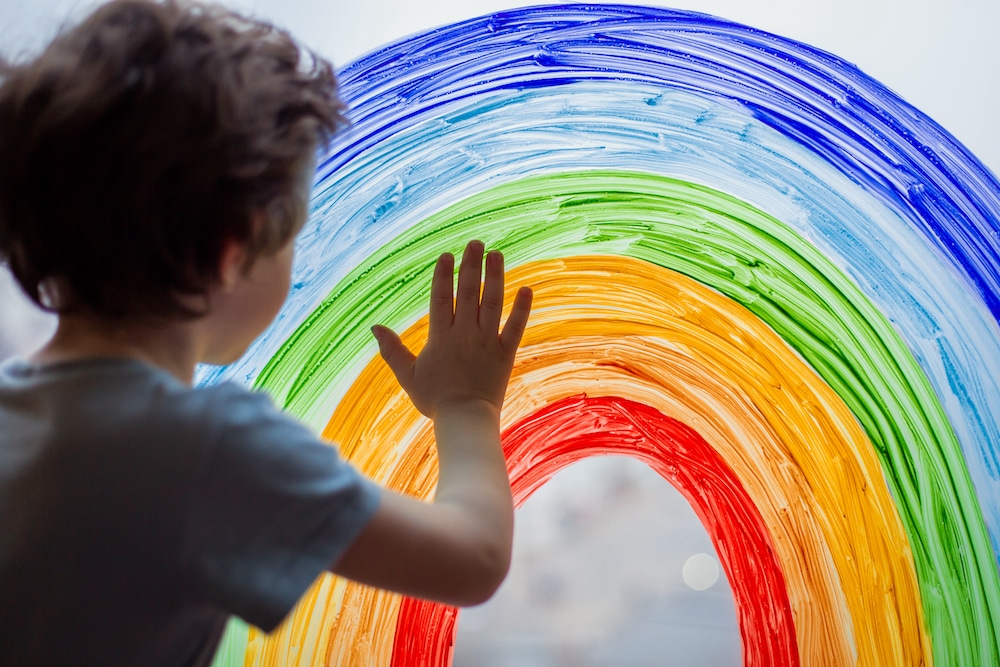Child at home draws a rainbow on the window. Autism and Gender Identity