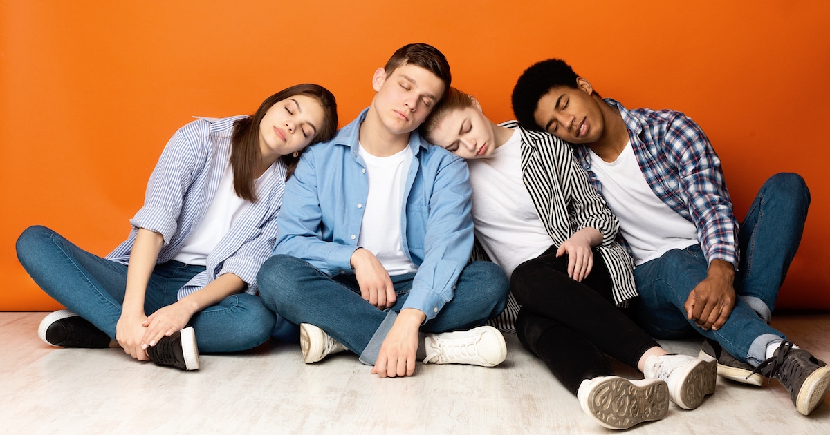 Tired teens sleeping on each other shoulders at school.