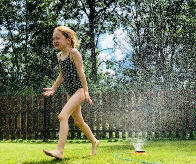 kid enjoying sprinkler in summer therapy for kids